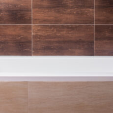 Close-up of white bathtub and brown tiles in new bathroom